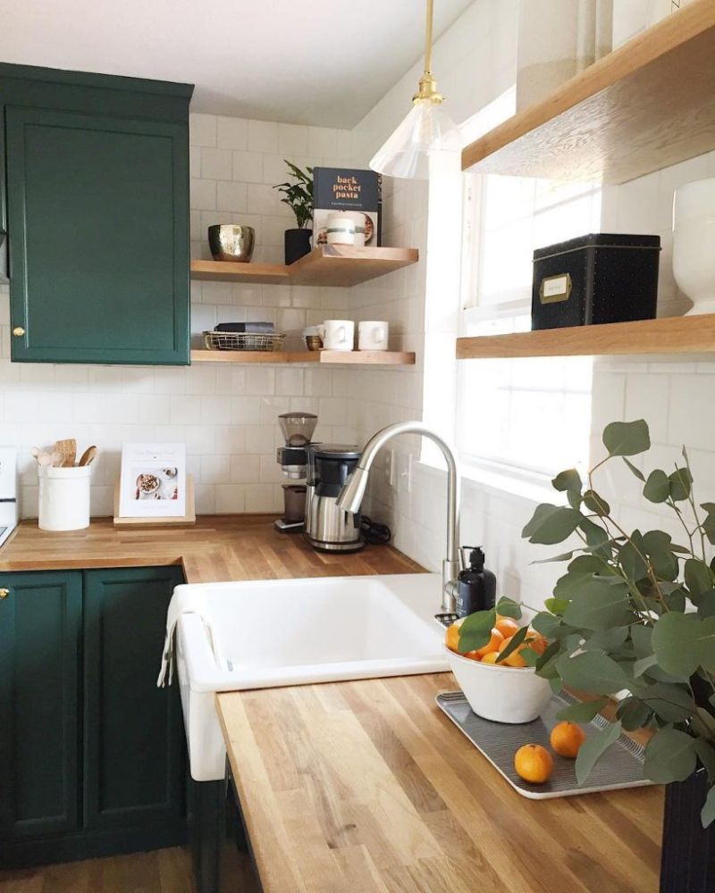 Стриманий темно-зелений колір кухонних меблів у поєднанні з білим і натуральним деревом створює відчуття затишку.