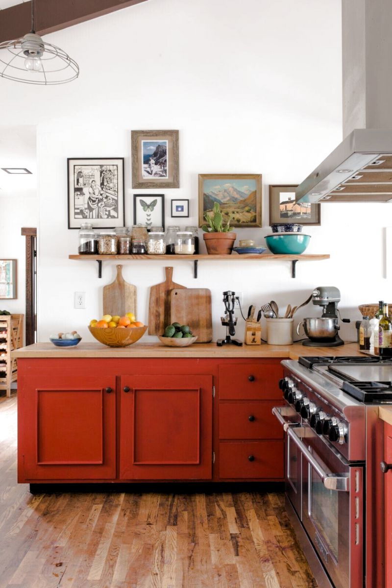 Кухонні меблі, пофарбовані не надто яскравою червоною фарбою ідеально доповнюють інтер'єр з купою деталей з натуральної деревини