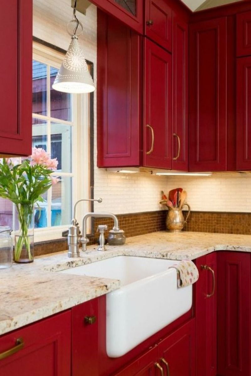 Червоні меблі, мармурові поверхні, мозаїчна плитка природних кольорів створюють вишуканий інтер'єр у кухні